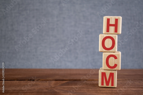 Abbreviation HOCM (hypertrophic obstructive cardiomyopathy) text acronym on wooden cubes on dark wooden backround. Medicine concept.