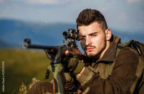 Hunt hunting rifle. Hunter man. Shooter sighting in the target. Hunting period. Male with a gun. Close up. Hunter with hunting gun and hunting form to hunt. Hunter is aiming. The man is on the hunt