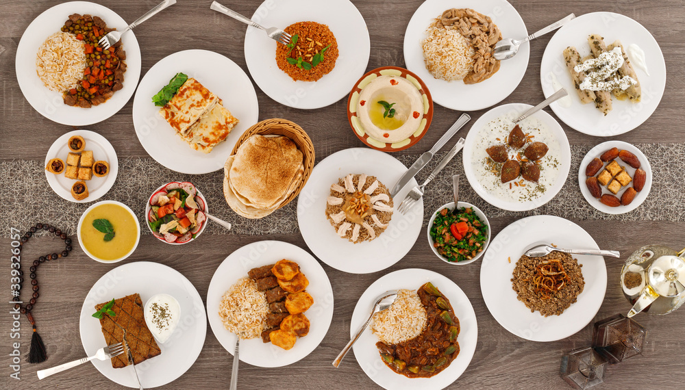 Iftar. Arabic family dinner. Ramadan Kareem, Eid Mubarak. Top view of table with sharing plates food. Lebanese cuisine. Starters, hummus, baklava, dates. Muslim people. Iftar. Arabic family dinner. Ramadan Kareem, Eid Mubarak. Top view of table with sharing plates food. Lebanese cuisine. Starters, hummus, baklava, dates. Muslim people.