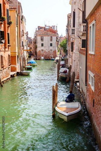 A venetian quiet channel with parked motor boats in summer day