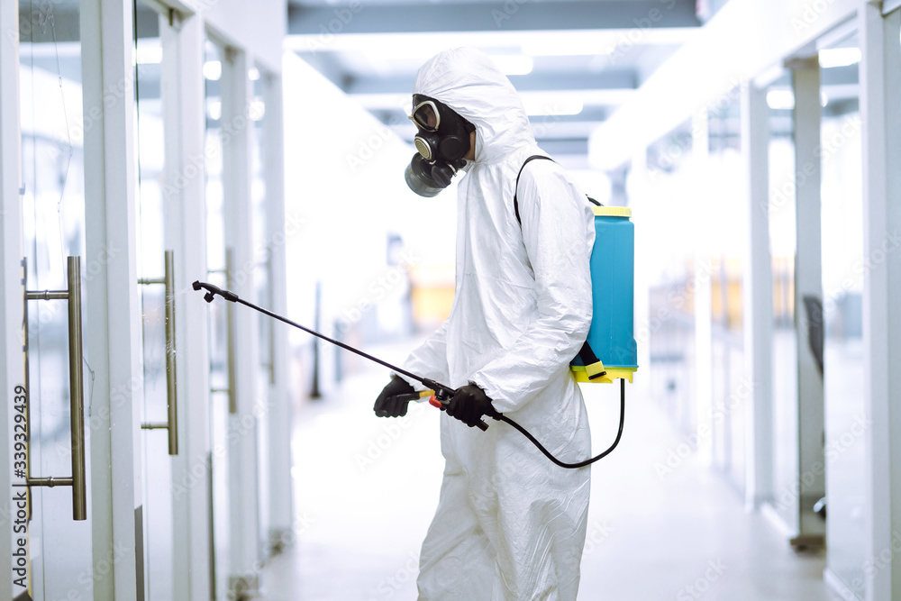 Disinfecting of office to prevent COVID-19, Man in protective hazmat suit with  with spray chemicals to preventing the spread of coronavirus, pandemic in quarantine city. Cleaning concept.