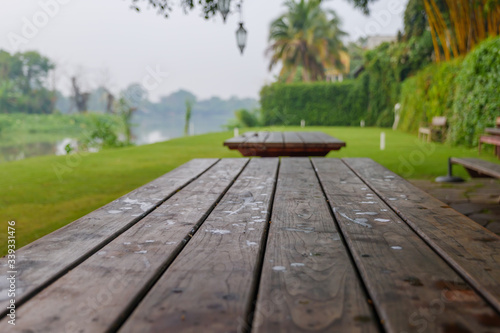Perspective view over rough wooden table with background of garden on riverside and natural green scenery in Asia. 
