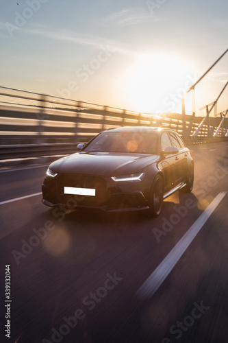 Black sedan car on the bridge in the sunset