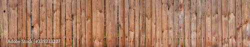 Texture of a wide wooden fence. Old rustic fence made of planks.