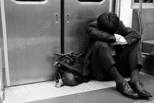 電車のドアの前でうずくまるサラリーマン