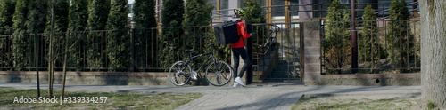 Delivery man courier wearing medical mask ringing at the door of residential building, food delivery to customers during virus outbreak. Coronavirus, COVID-19, safe delivery