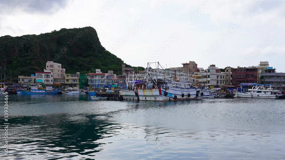 Asian fishing boats anchored in port. Taiwanese multi-colored fishing trawler moored in bay on background of green mountains,
Fishing industry in Asia. fishermen prepare gear