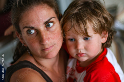 Mother and young son look off in a somber and serious manner