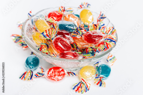 Bowl full with mix hard wrapped candies isolated on white background.