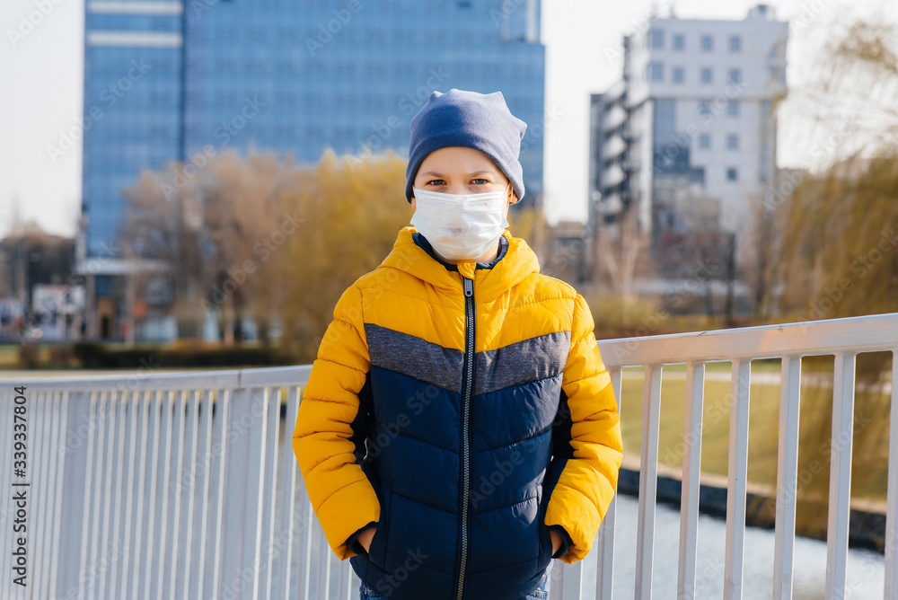 A boy stands on a gray background in a mask during a quarantine with free space. Quarantine in the mask A boy stands on a gray background in a mask during a quarantine with free space. Quarantine in the mask