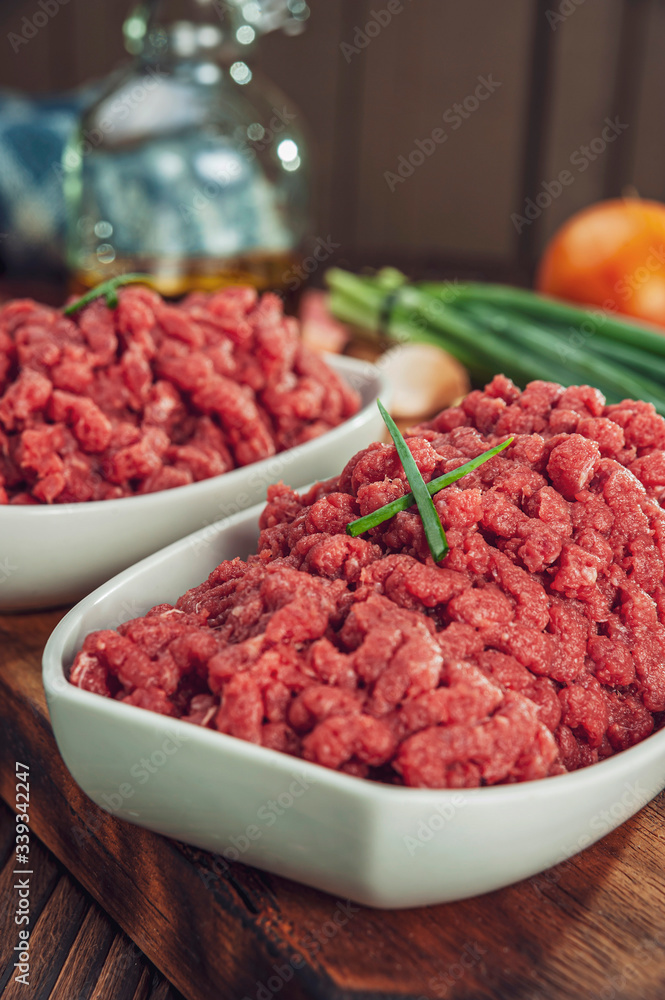 Raw ground beef in closeup with ingredients - ready for cooking Raw ground beef in closeup with ingredients - ready for cooking