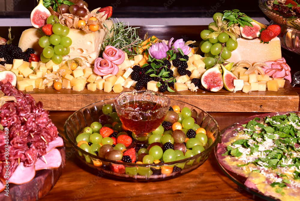 Fototapeta premium delicious portion with grape figs, strawberries, cheese, ham, raspberries and seasoning served on rustic wooden board with blurs