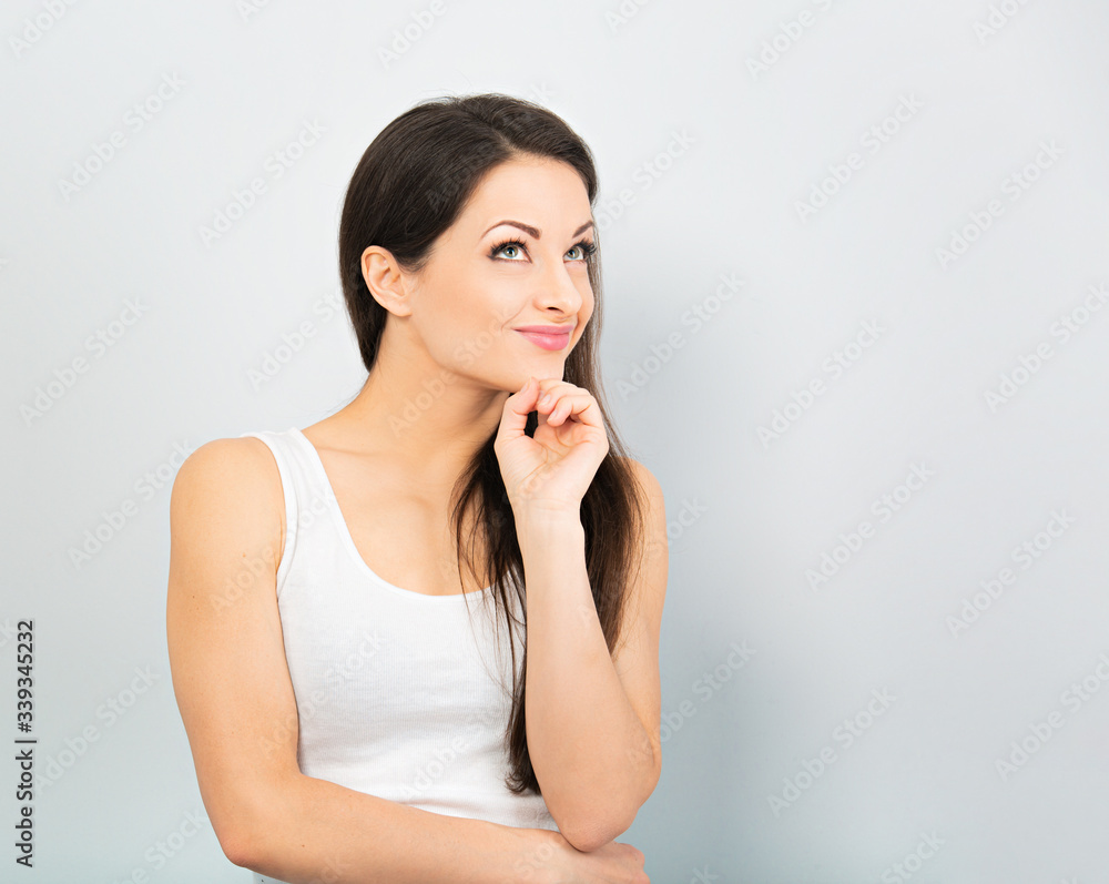 Beautiful positive young happy woman with hand under the face thinking and looking up in casual white t-shirt and long hair. Closeup Beautiful positive young happy woman with hand under the face thinking and looking up in casual white t-shirt and long hair. Closeup