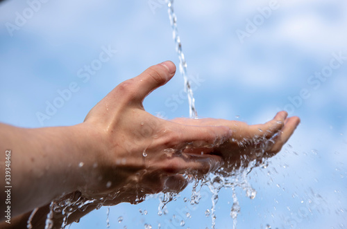 Clear Water flows down on men's hands against the sky. © FO_DE