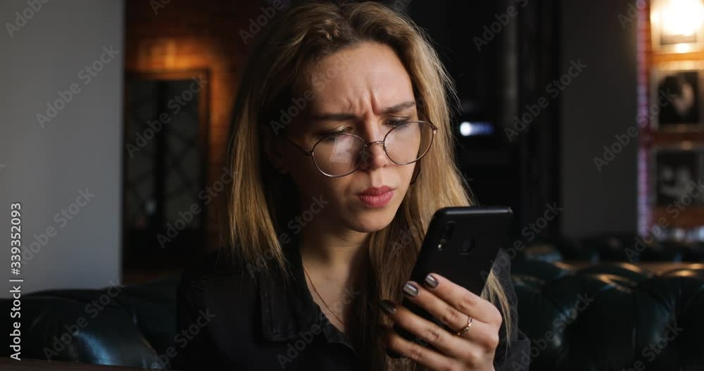 Close Up Portrait of Teen Girl with Beautiful Smile in Glasses is Using Smartphone at Day In Cafe. Casual Lifestyle. Blurred Bokeh Background. 4K Close Up Portrait of Teen Girl with Beautiful Smile in Glasses is Using Smartphone at Day In Cafe. Casual Lifestyle. Blurred Bokeh Background. 4K