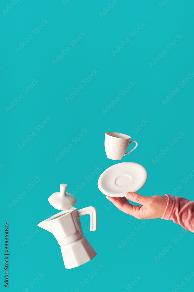 Trendy levitation Flying coffee beans, espresso cup with saucer balancing on index finger of female hand. Ceramic coffee maker levitation. Trendy mint blue coffee background, space for your text. Trendy levitation Flying coffee beans, espresso cup with saucer balancing on index finger of female hand. Ceramic coffee maker levitation. Trendy mint blue coffee background, space for your text.