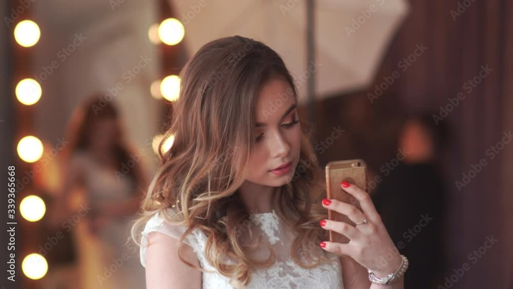 Beautiful girl model posing in front of a mirror and taking pictures on a smartphone. Beautiful girl model posing in front of a mirror and taking pictures on a smartphone.