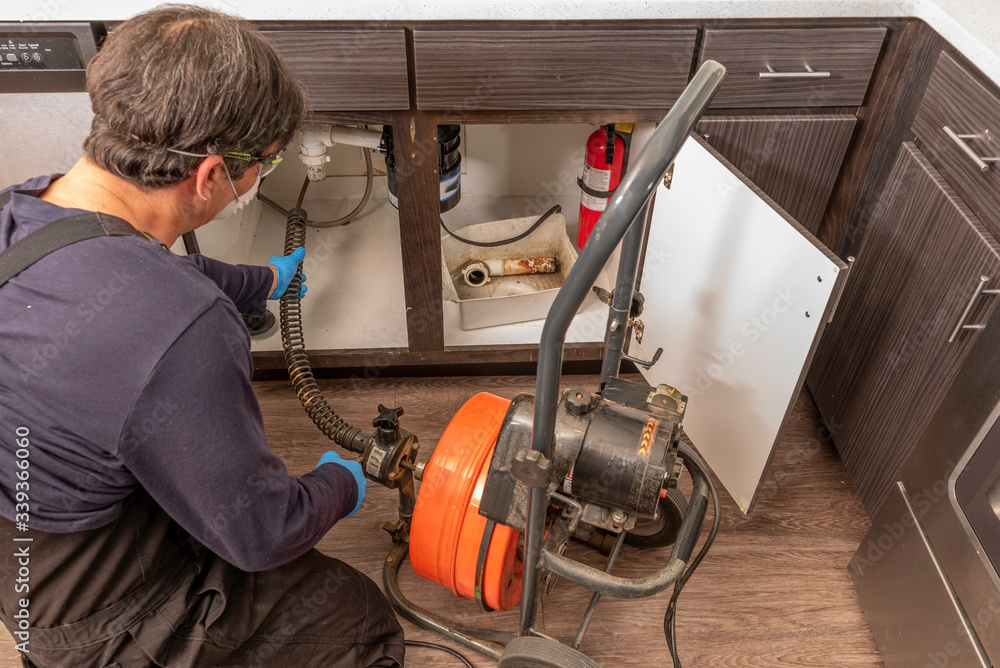 Plumber Snaking a Kitchen Sink Drain Foto Stok Adobe Stock