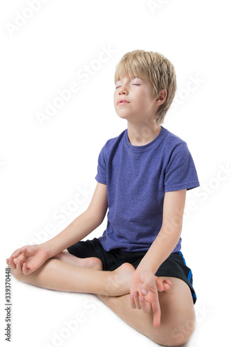 Young boy sitting practicing meditation, isolated on white background 