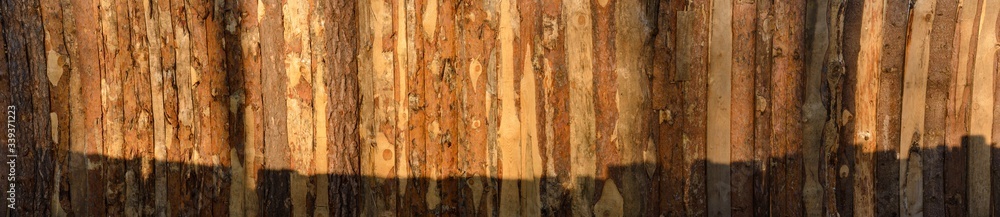 A panoramic fragment of a wooden fence made of a pine Board with a shadow from the neighboring fence