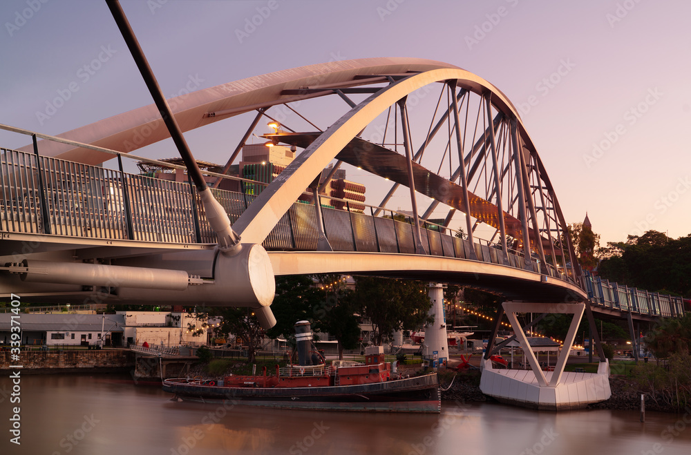 Naklejka premium Brisbane goodwill Bridge with tug boat forcefull underneath at sunset