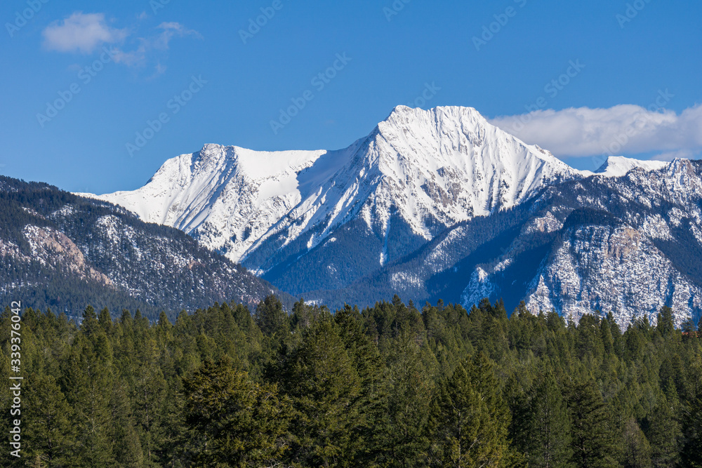 view of the mountain range with trees and snow on it sunny spring day. view of the mountain range with trees and snow on it sunny spring day.