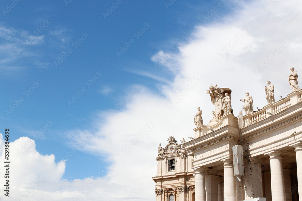 Fototapeta premium A group of Saint Statues on the colonnades of St Peter's Square with blue sky and clouds in Vatican City, Rome, Italy