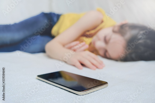 Girl sleeps at home on the couch next to the iPhone