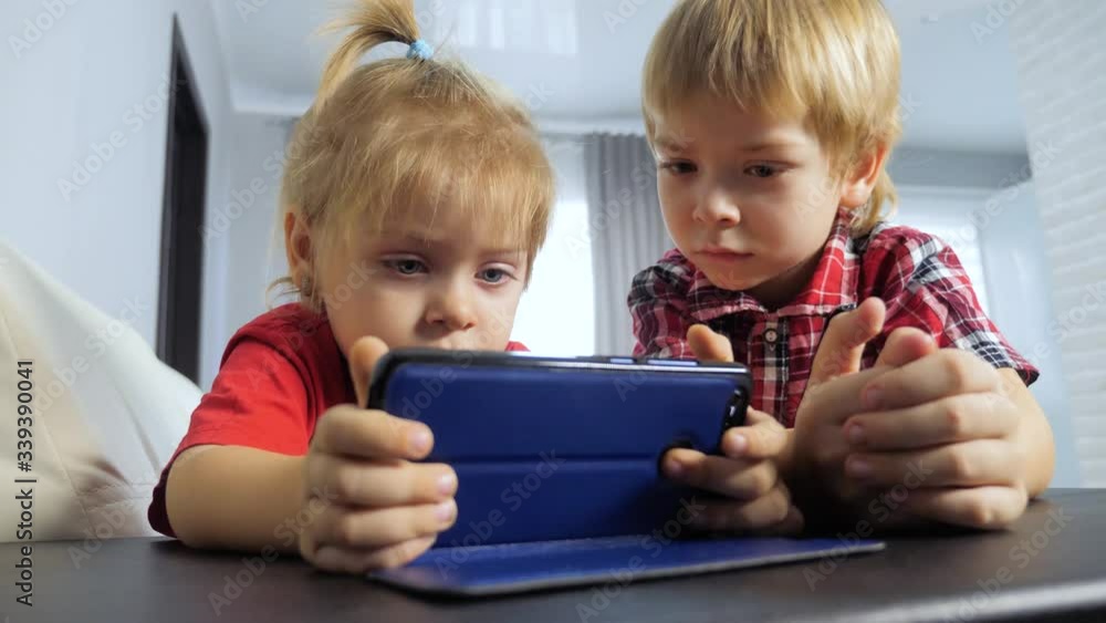 children watch online video cartoons on a smartphone. kids little boy and girl brother sister watch online streaming lifestyle broadcasting on the phone children watch online video cartoons on a smartphone. kids little boy and girl brother sister watch online streaming lifestyle broadcasting on the phone
