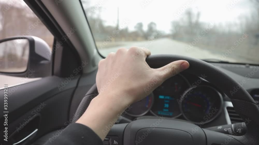 Driver's Hand On The Steering Wheel Of A Car Driving On The Asphalt Road - Closeup Shot Driver's Hand On The Steering Wheel Of A Car Driving On The Asphalt Road - Closeup Shot
