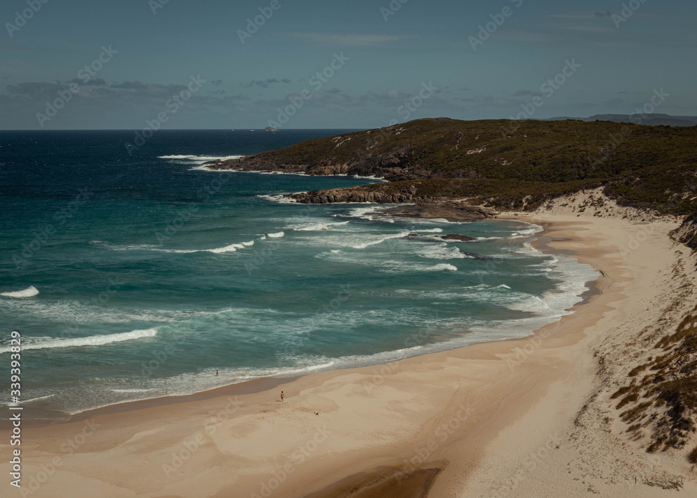 Sight on a big broad beach from a viewpoint in a remote place in Western Australia. The color of the sand and the water are reflecting the idea of a warm summer