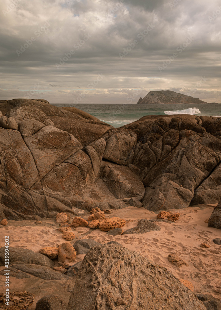 Obraz premium Dramatic scenery with rough water smashing rocks with an isolated island in the background. This takes place in a remote area in Western Australia