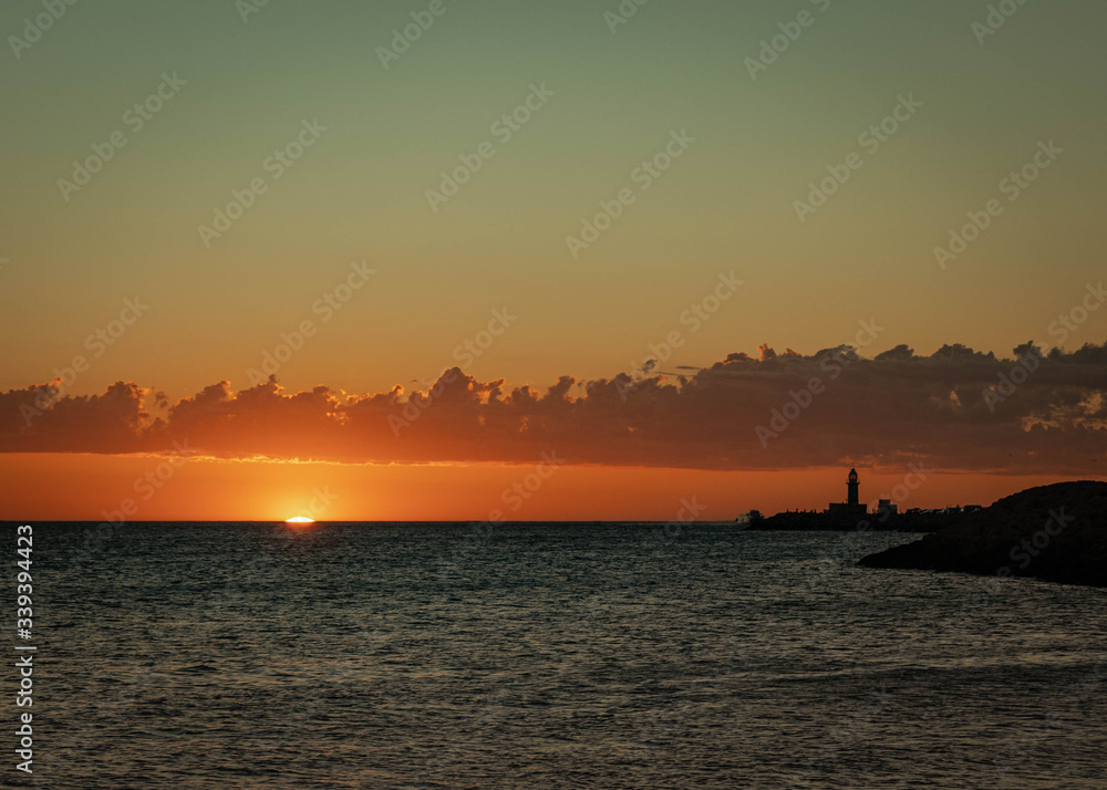 Sunset at the beach in Fremantle, Western Australia. The atmosphere was really quiet as the sun came down, displaying beautiful warm colors. The lighthouse on the pier is in a silhouette.