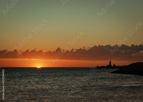 Sunset at the beach in Fremantle, Western Australia. The atmosphere was really quiet as the sun came down, displaying beautiful warm colors. The lighthouse on the pier is in a silhouette. © Nolan