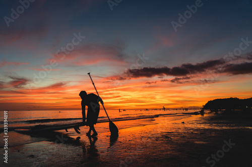 silhouette of a surfer man with his surfboard on the beach during orang sunset