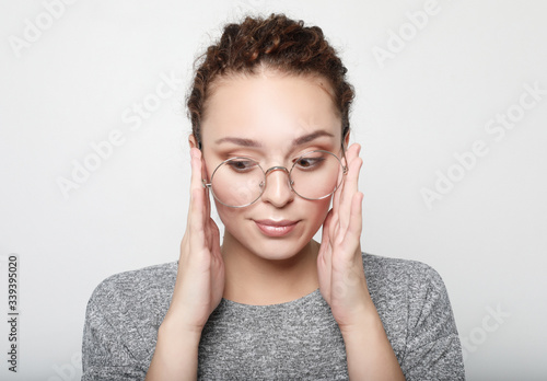 Positive female student wears grey sweater, round glasses.People, studying, success and achievements.