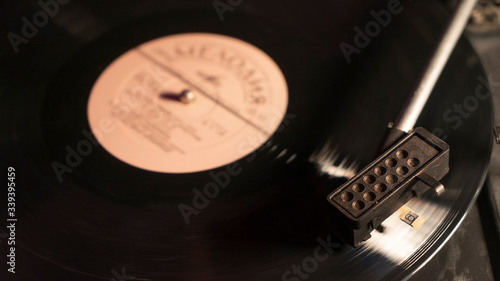 A vinyl record close-up on a dark background. Close up of turntable tonearm playing vinyl record.