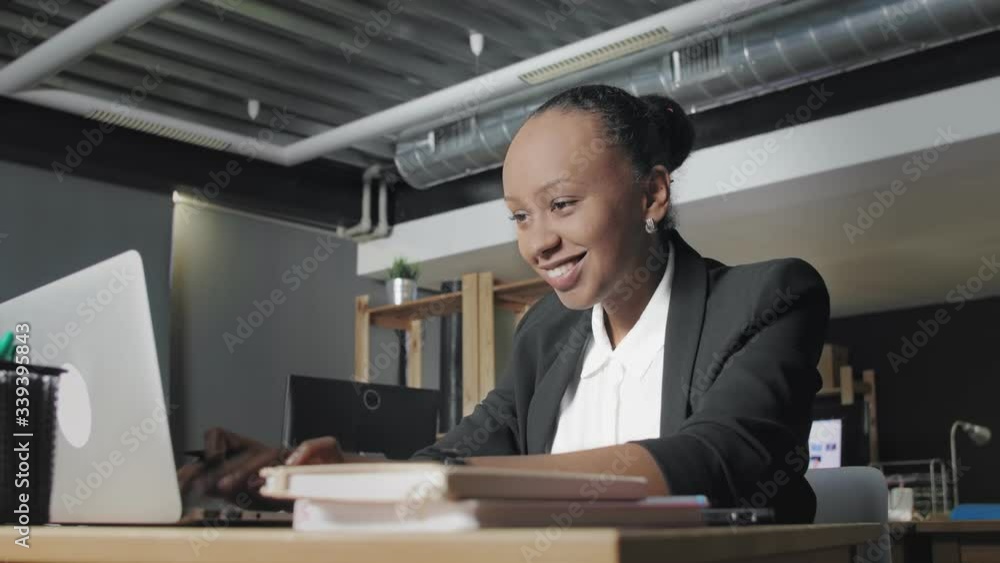 Side view of happy young african american woman feeling success and working better in coworking office Side view of happy young african american woman feeling success and working better in coworking office
