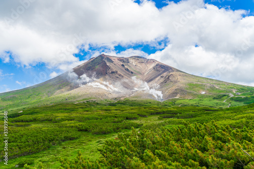 Scenery of Asahidake peak mountain and blue cloudy sky in summer, Asahikawa, Hokkaido, Japan. The tallest mountain in Japanese island of Hokkaido and located in the Daisetsuzan National Park
