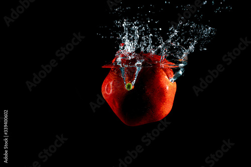 Pomegranate fruit drop to water splash isolated with black background