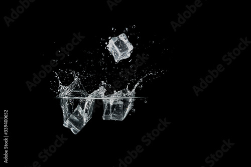 ice cubes drop to water, isolated with black background © thanarak