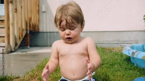 Toddler sneezes twice while sitting in the sun in backyard slow motion
