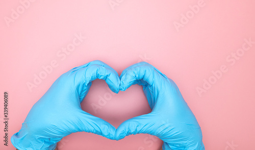 Medical gloves blue Heart shaped hand symbol on pink background with copy space  Health care concept..