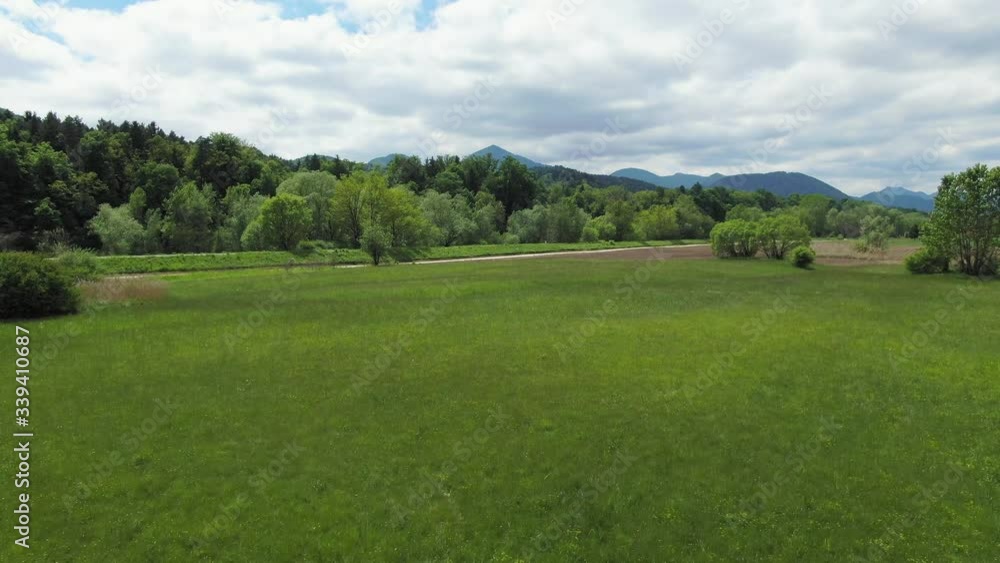 Fast drone flies low over green grass toward river and turns quickly right Fast drone flies low over green grass toward river and turns quickly right