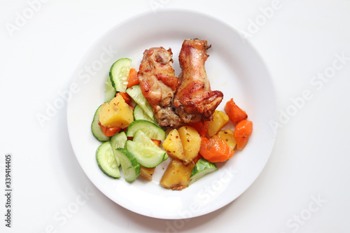 Grilled chicken wings with vegetables in a plate on white background