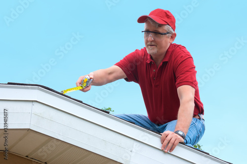 Wind mitigation inspector wearing safety goggles doing inspection on new roof to create a report and risk rating for homeowner to send to their insurance company to receive deductions in policy costs.