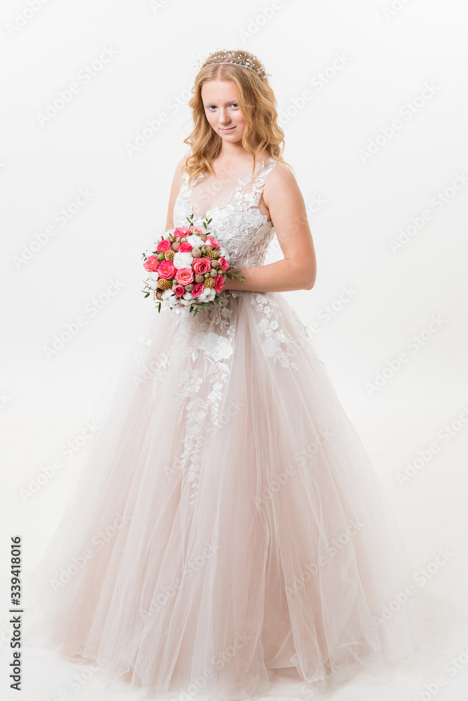 Portrait of romantic young bride in white lace wedding dress with fantasy makeup and wavy blonde hair with wedding bouquet in her hands getting ready in bride's morning. Fine art wedding. Portrait of romantic young bride in white lace wedding dress with fantasy makeup and wavy blonde hair with wedding bouquet in her hands getting ready in bride's morning. Fine art wedding.