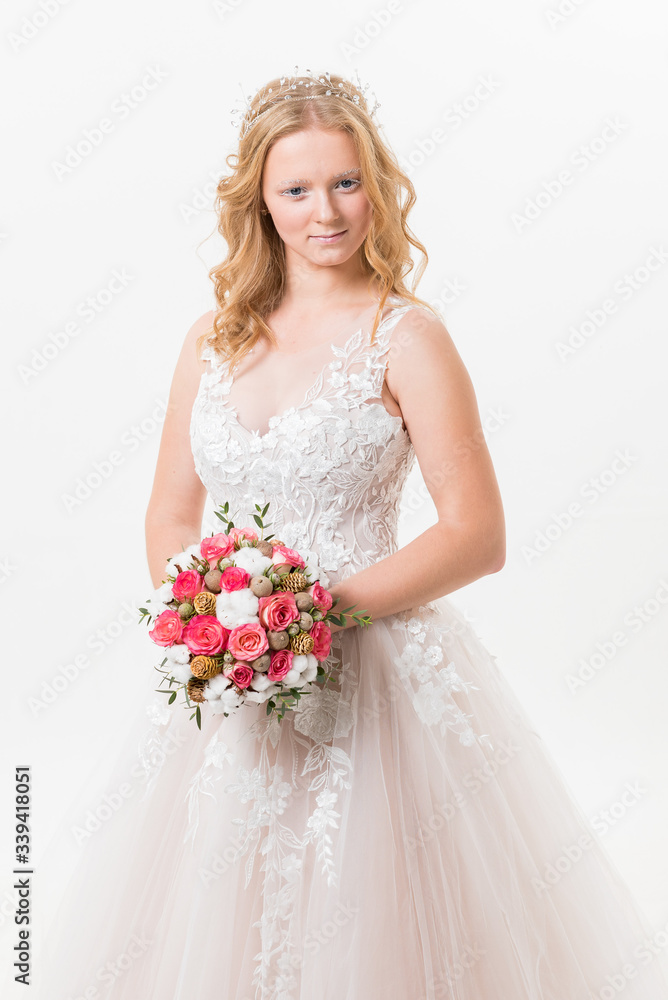 Portrait of romantic young bride in white lace wedding dress with fantasy makeup and wavy blonde hair with wedding bouquet in her hands getting ready in bride's morning. Fine art wedding. Portrait of romantic young bride in white lace wedding dress with fantasy makeup and wavy blonde hair with wedding bouquet in her hands getting ready in bride's morning. Fine art wedding.