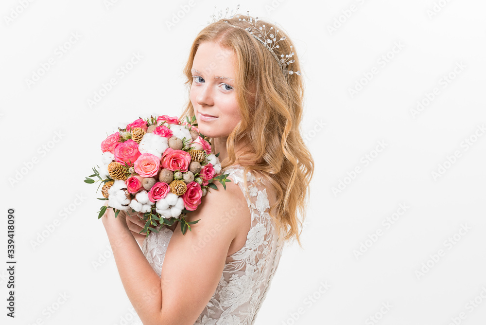 Portrait of romantic young bride in white lace wedding dress with fantasy makeup and wavy blonde hair with wedding bouquet in her hands getting ready in bride's morning. Fine art wedding. Portrait of romantic young bride in white lace wedding dress with fantasy makeup and wavy blonde hair with wedding bouquet in her hands getting ready in bride's morning. Fine art wedding.