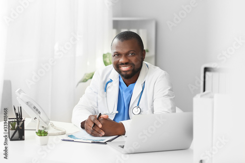 Male African-American doctor at table in clinic